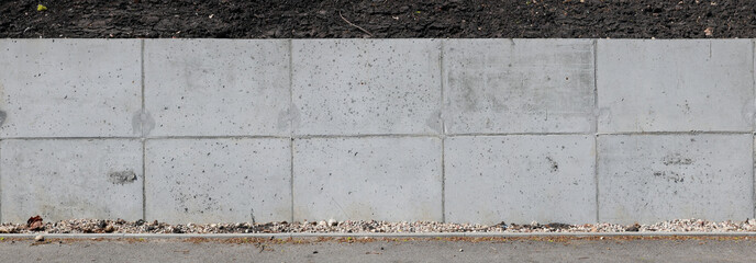 A long concrete wall supports the  slope and protects the earth from shedding.