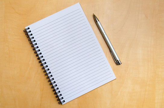 Open spiral notebook and pen on a wooden table
