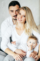 Young family posing and smiling at camera. Mother, father and son. Indoor