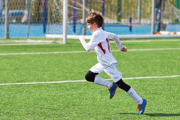 Running boy soccer player training on football field