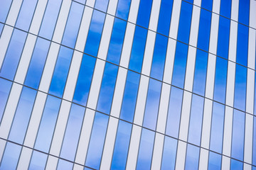 Fototapeta premium Blue sky and white clouds reflected in the glass and metal of a modern architectural highrise.