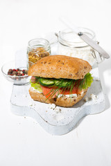 sandwich with salted fish, vegetebles and cream cheese on white wooden board, vertical