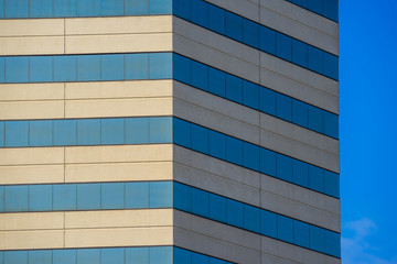 Angled lines of modern skyscraper stand beside an expanse of blue sky.