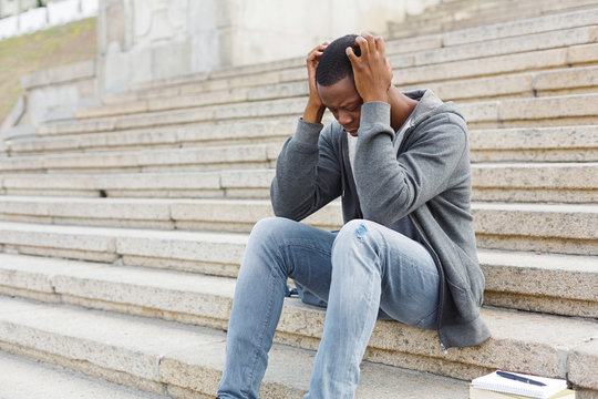 Stressed african-american man sitting on stairs
