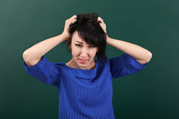 woman teacher in stress posing by chalk Board, tears her hair, learning concept, green background, Studio shot