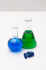 Chemistry glasses filled with colorful liquids and blue pills