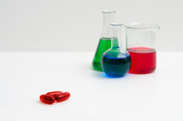 Chemistry glasses filled with colorful liquids and red pills