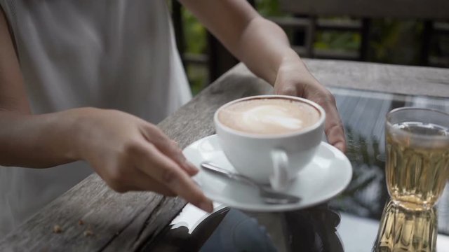 Slow motion woman hand holding and pass serving a hot coffee in white cup.
