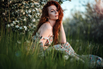 red-haired girl in a blooming garden