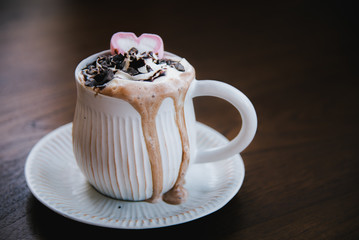 Hot chocolate in a vintage cup With cream overflow. Sprinkle with chocolate chips and heart-shaped marshmallows. Put on the table