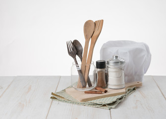 Chef hat ,spoons, salt and spices on table,white background