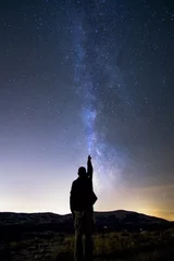  Un homme qui éclaire le ciel étoilé lors d’une belle nuit claire d’été © feng33