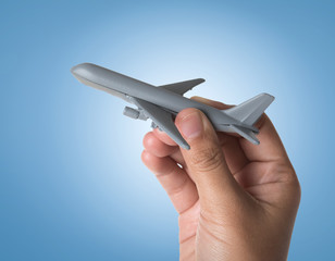 Hand holding miniature airplane on blue background