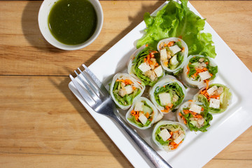 Spring roll with seafood dip on wooden background top view.