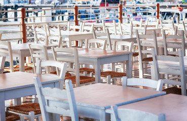 Empty white chairs and tables in harbor cafe.