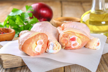Raw chicken legs on a cutting board on an old wooden table.