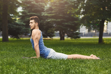 Man training yoga in cobra pose outdoors