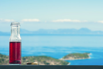 Obraz premium Pomegranate cold juice in bottles opposite on the islands and sea 