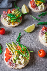 Bruschetta with tomato, avocado, herbs and arugula. Rustic background. Top view