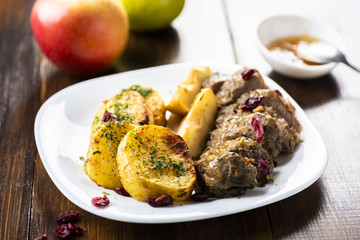 Duck fillet served with baked potatoes, apples and cranberries