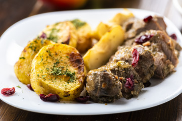 Duck fillet served with baked potatoes, apples and cranberries