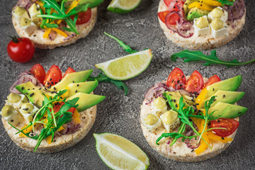 Bruschetta with tomato, avocado, herbs and arugula. Rustic background. Top view