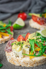 Bruschetta with tomato, avocado, herbs and arugula. Rustic background. Top view
