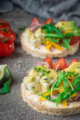 Bruschetta with tomato, avocado, herbs and arugula. Rustic background. Top view