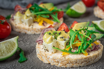 Bruschetta with tomato, avocado, herbs and arugula. Rustic background. Top view