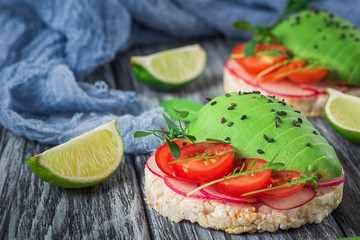 Bruschetta with tomato, avocado, herbs and arugula. Rustic background. Top view
