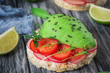 Bruschetta with tomato, avocado, herbs and arugula. Rustic background. Top view