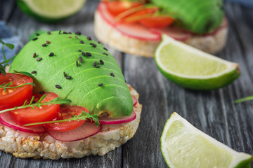 Bruschetta with tomato, avocado, herbs and arugula. Rustic background. Top view