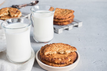 Fresh healthy milk and oatmeal cookies with cereals on grey concrete background