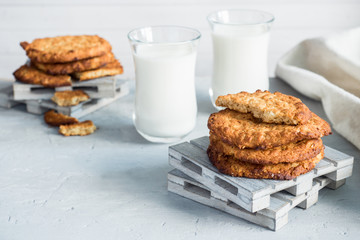 Fresh healthy milk and oatmeal cookies with cereals on grey concrete background