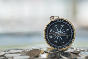 Fototapeta na wymiar Business concept. Close up of vintage compass on pile of silver coins.
