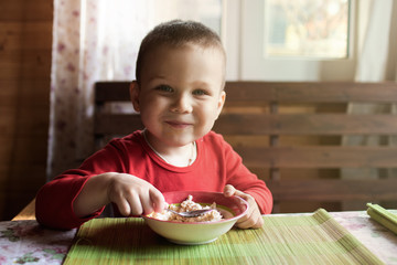 The little boy looks at the camera while eating breakfast.