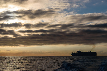 Maritime Industry Meets Nature: Large Freighter Under Cloudy Skies In Open Seas 