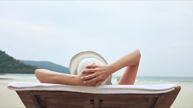 Young beautiful woman enjoying summer vacation on the lounger, beach relax, summer in tropics