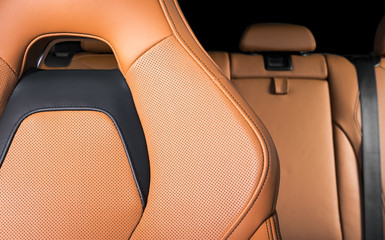 Part of red leather car seat with the unfocused car interior on the background