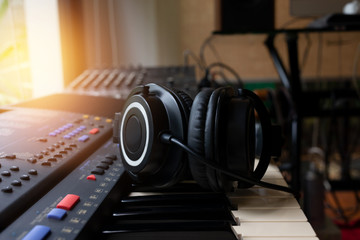Plakat Musical instruments..Electric piano and headphone close up at eye level angle with defocused audio mixer and monitor speakers in background.