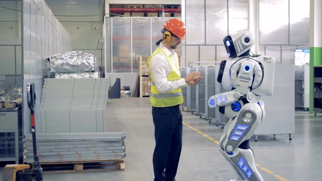 Factory cyborg is getting instructions from a male engineer