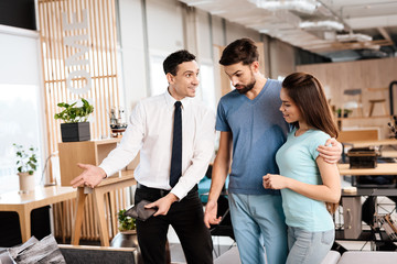 The furniture store manager demonstrates furniture to the buyers.