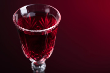Close-up of crystal glass with red wine on dark background.