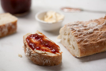 Homemade french bread baguette sliced with strawberry jam and butter