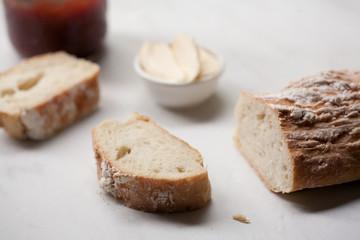 Fototapeta na wymiar Homemade french bread baguette sliced next to butter and homemade jam