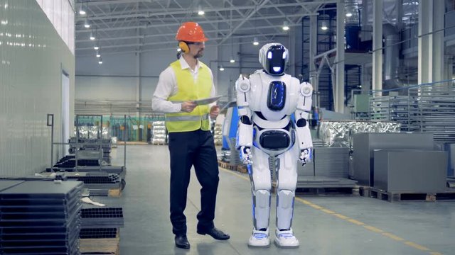 Human-like cyborg is getting switched on and set up by a male factory worker