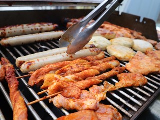 Various assorted meat on a grill. Grilling season concept. Sausages, meat rolls, grilled tofu. Delicious eating. Top view, close up