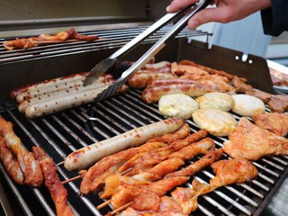Various assorted meat on a grill. Grilling season concept. Sausages, meat rolls, grilled tofu. Delicious eating. Top view, close up