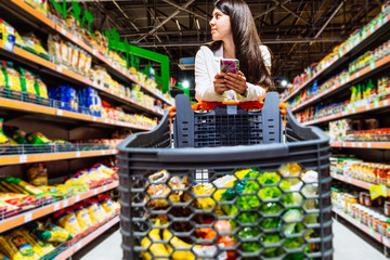 woman with smartphone in store. grocery shopping. gadgets and shopping.
