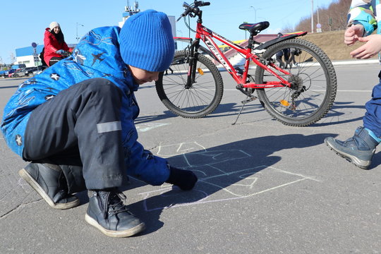 Russia, Severomorsk - 01 May 2018: The boy paints on the asphalt in the spring on the square
